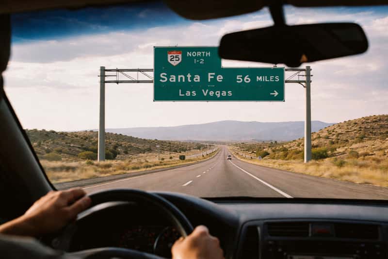 Highway 285 stretching north from Albuquerque toward Santa Fe mountains under clear sky